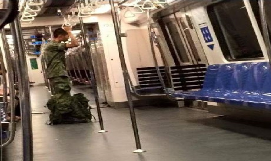MAN IN ARMY UNIFORM STANDING DESPITE MANY SEAT AVAILABLE!!