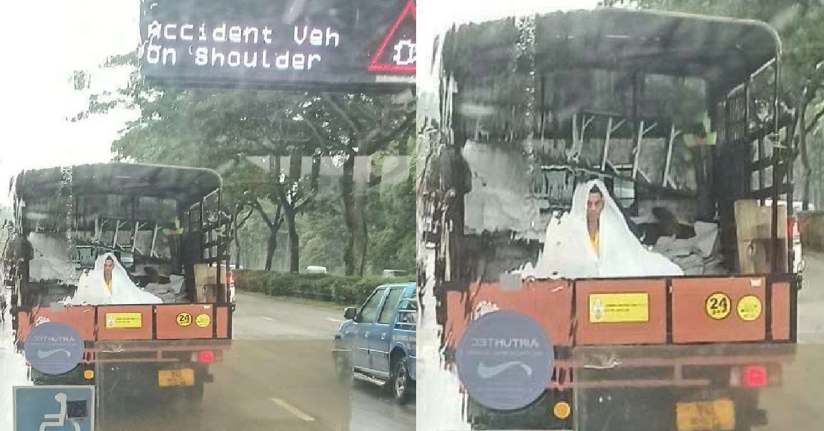 POOR WORKER SITTING AT BACK OF LORRY IN THE RAIN, WEARING ONLY RAINCOAT