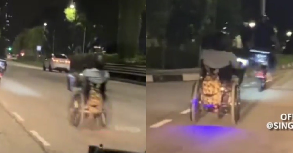 MAN RIDING ELECTRIC WHEELCHAIR WITH HELMET ON THE ROAD