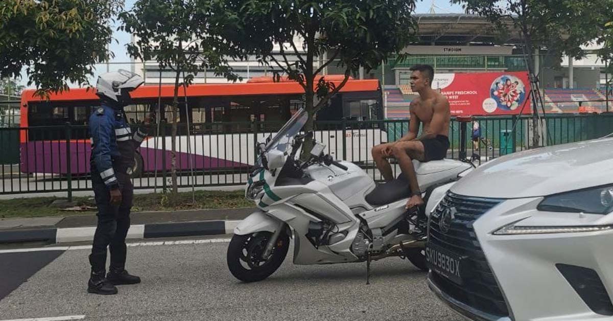 SHIRTLESS MAN SITTING ON MOTORBIKE IN MIDDLE OF ROAD