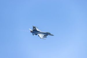 a fighter jet flying through a blue sky